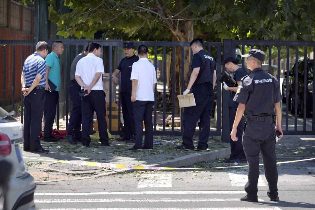 Officials and security personnel stand near the site of reported blast just south of the U.S. Embassy in Beijing, Thursday, July 26, 2018. (AP Photo/Mark Schiefelbein)
