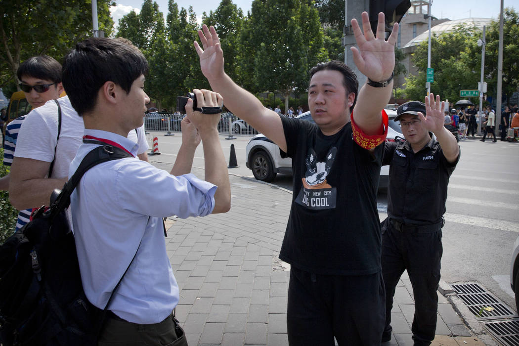 Chinese officials try to prevent journalists from filming near the site of a reported blast near the U.S. Embassy in Beijing, Thursday, July 26, 2018. (AP Photo/Mark Schiefelbein)