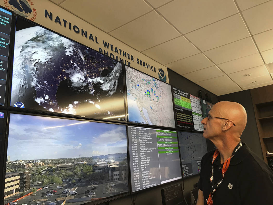 In this Wednesday, July 18, 2018 photo, National Weather Service forecaster Marvin Percha reviews monitors that track satellite and Doppler radar images, as well as his colleagues' forecasts poste ...