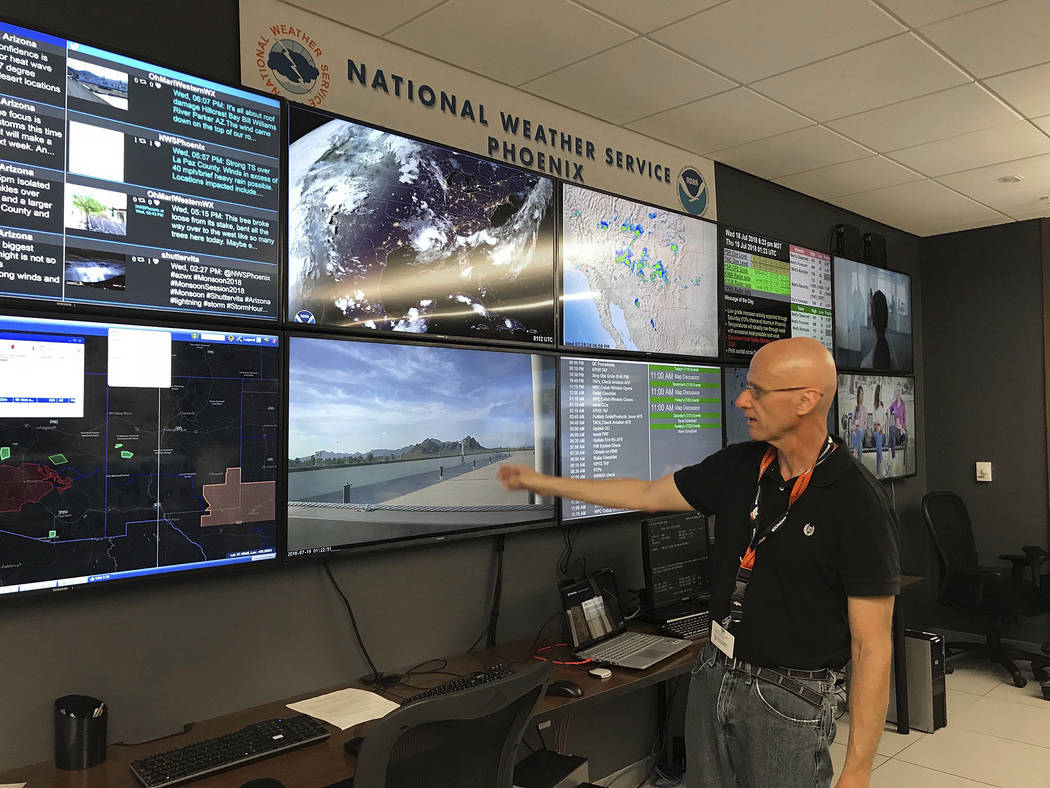 In this Wednesday, July 18, 2018 photo, National Weather Service forecaster Marvin Percha reviews monitors that track satellite and Doppler radar images, as well as his colleagues' forecasts poste ...