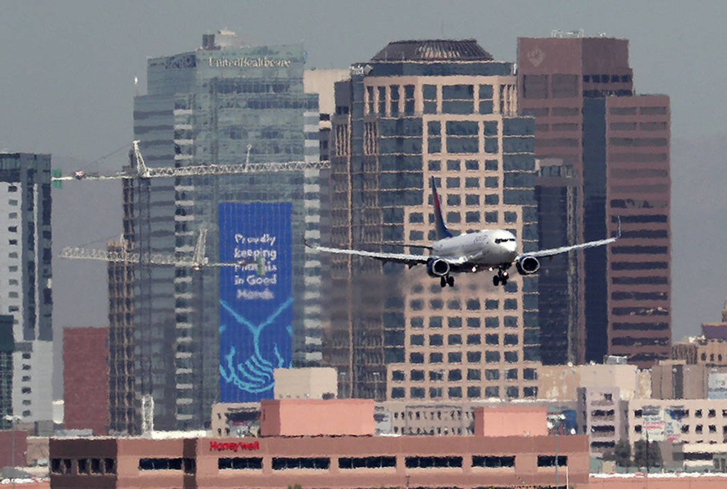 In this Monday, July 23, 2018 photo, heat ripples blur the downtown skyline as a jet lands in Phoenix, Ariz., as temperatures exceed 100 degrees in the morning hours. (AP Photo/Matt York)
