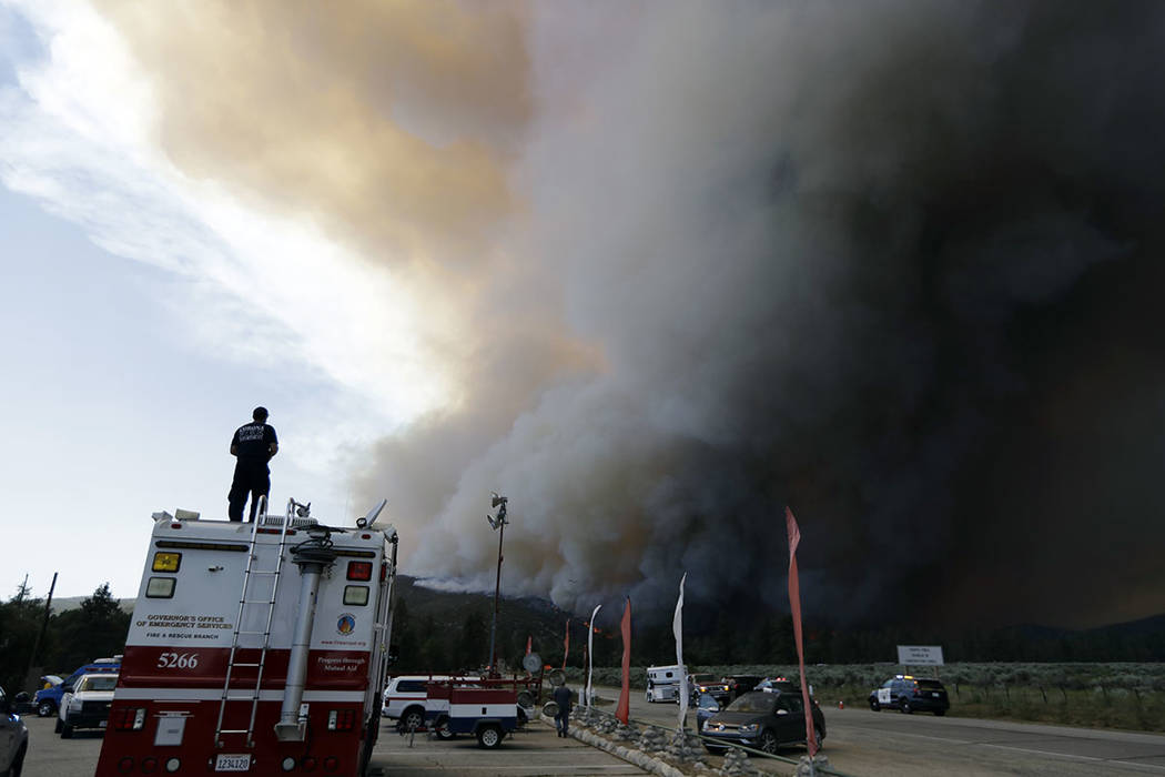 Smoke from a wildfire rises over highway 74, Thursday, July 26, 2018, in Mountain Center, Calif. A fast-moving wildfire, believed to have been sparked by arson, tore through trees, burned homes an ...