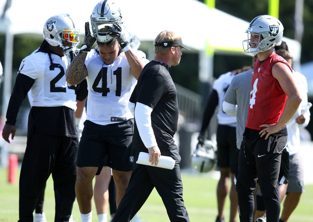 Oakland Raiders head coach Jon Gruden walks past running back Marshawn Lynch (24), left, running back Keith Smith (41) and quarterback Derek Carr (4), right, at the Oakland Raiders training camp i ...