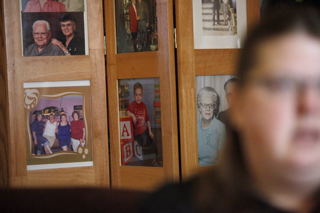 Photos of family and Daemion Olsen, center, behind Carrie Olsen as she talks about the health issues of her son to the Review-Journal at her home in Las Vegas, Tuesday, July 31, 2018. Medicaid ann ...
