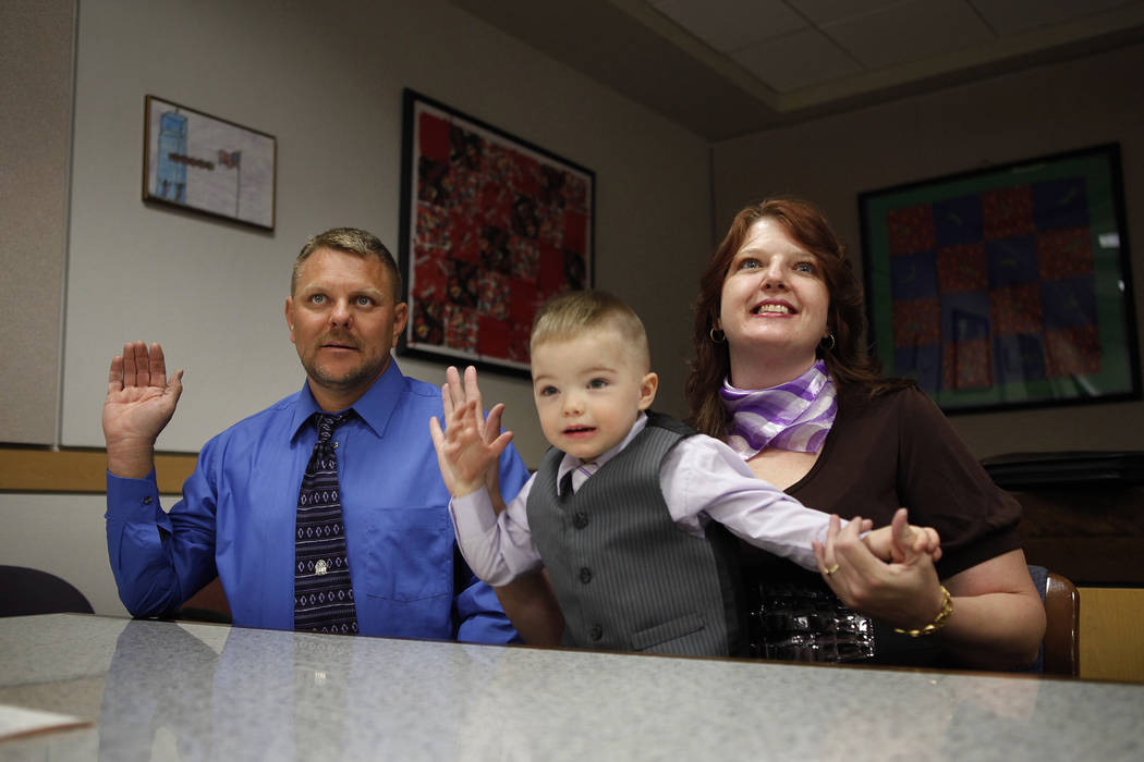Three-year-old Daemion Olsen mimics his mother Carrie Olsen, right, and father Jeff Olsen as they are sworn-in during an adoption hearing at the Family Courts and Services Center in Las Vegas Tues ...