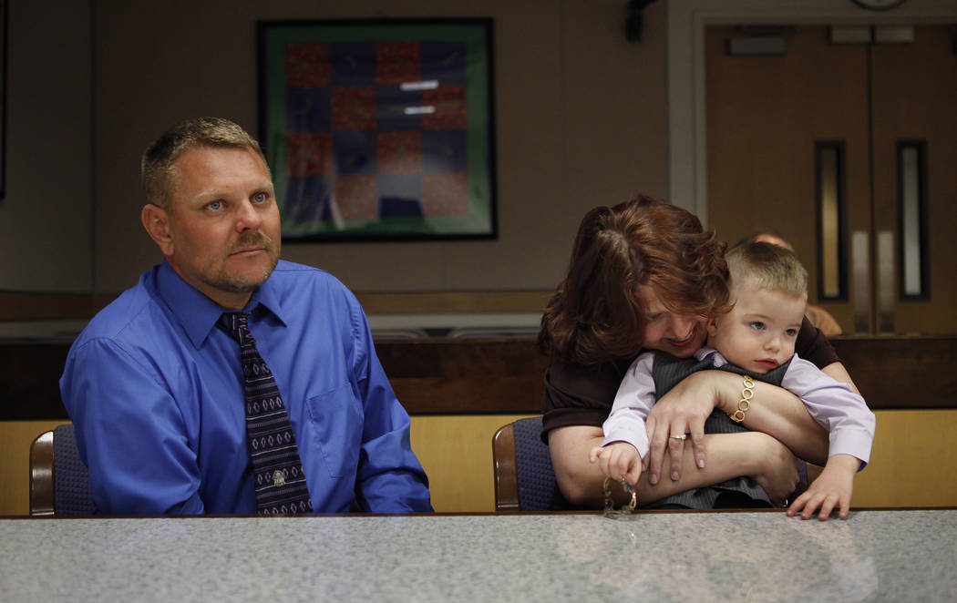 Three-year-old Daemion Olsen gets hugged by his mom Carrie Olsen as Jeff Olsen sits next to them during an adoption hearing at the Family Courts and Services Center in Las Vegas Tuesday, March 13, ...