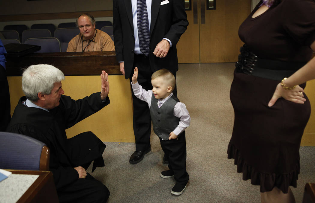 Three-year-old Daemion Olsen, center, gives a high-five to Judge Frank P. Sullivan after an adoption hearing at the Family Courts and Services Center in Las Vegas Tuesday, March 13, 2012. Carrie a ...