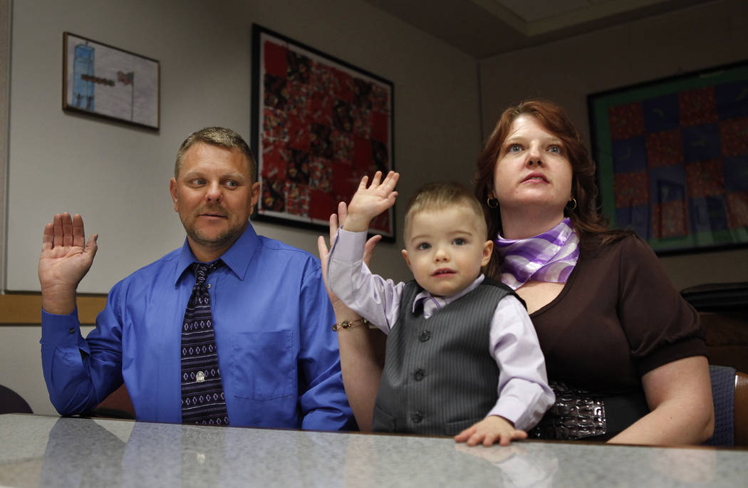Three-year-old Daemion Olsen mimics his mother Carrie Olsen, right, and father Jeff Olsen as they are sworn-in during an adoption hearing at the Family Courts and Services Center in Las Vegas Tues ...