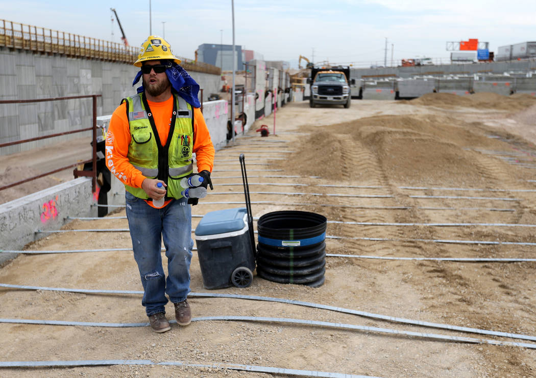 Mike Yedinak grabs bottles of water for his crew working on a retaining wall for the "Neon Gateway" high-occupancy vehicle exit ramps as part of Nevada Department of Transportation Proje ...