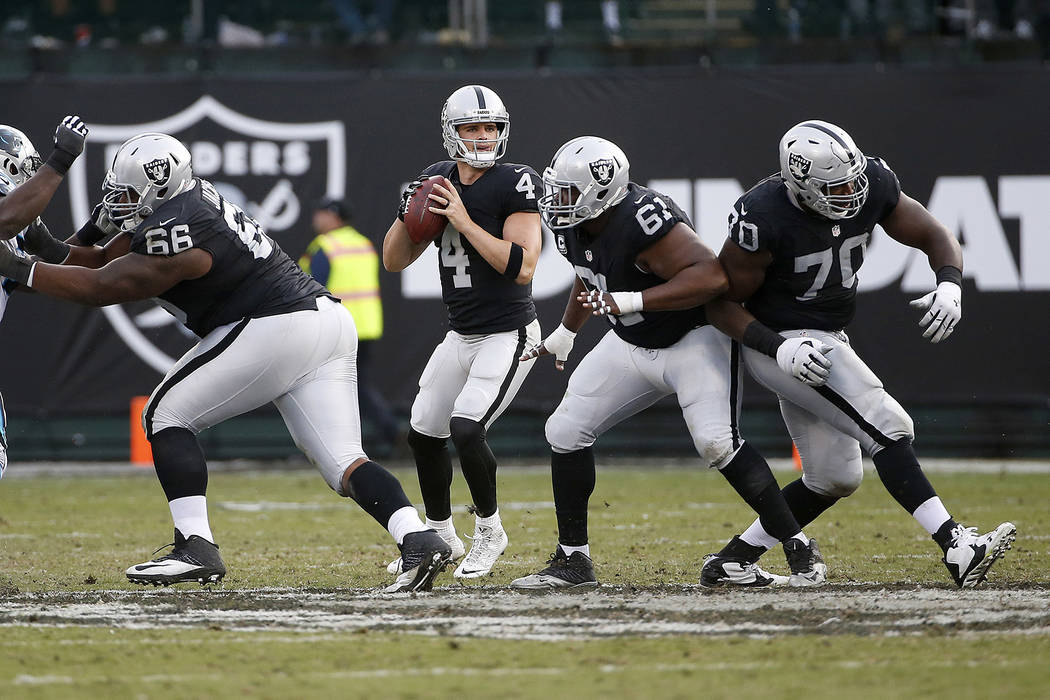 Oakland Raiders quarterback Derek Carr (4) passes behing guard Gabe Jackson (66), guard Rodney Hudson (61) and offensive guard Kelechi Osemele (70) during the second half of an NFL football game a ...