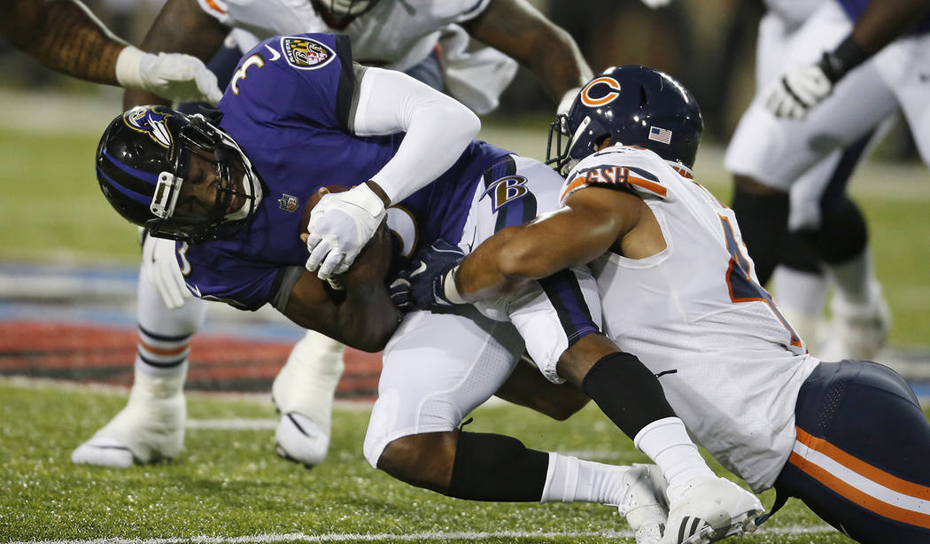 Chicago Bears linebacker Isaiah Irving, right, tackles Baltimore Ravens quarterback Robert Griffin III (3) during the first half of the Pro Football Hall of Fame NFL preseason game Thursday, Aug. ...