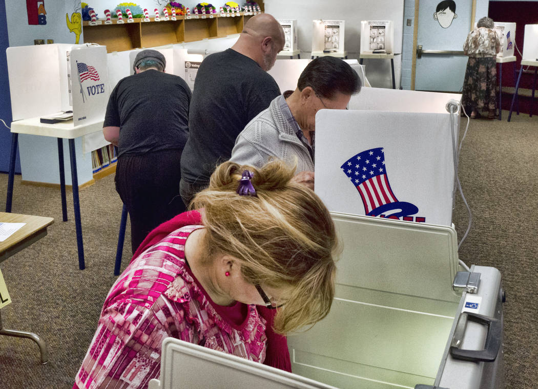 This June 5, 2018 file photo shows people marking their ballots at a polling station at Robert F. Kennedy Elementary School in Los Angeles. A security review found a software error caused a proble ...