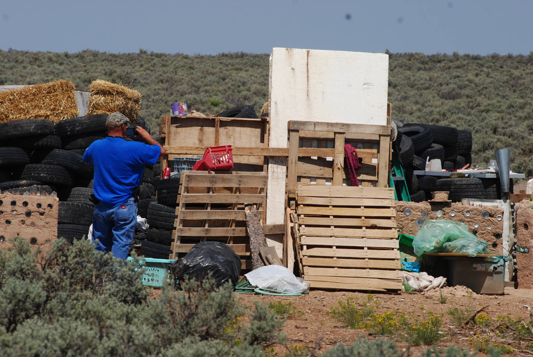 Taos County Solid Waste Department Director Edward Martinez surveys property conditions at a disheveled living compound at Amalia, N.M., Tuesday, Aug. 7, 2018. The investigation into a group of st ...
