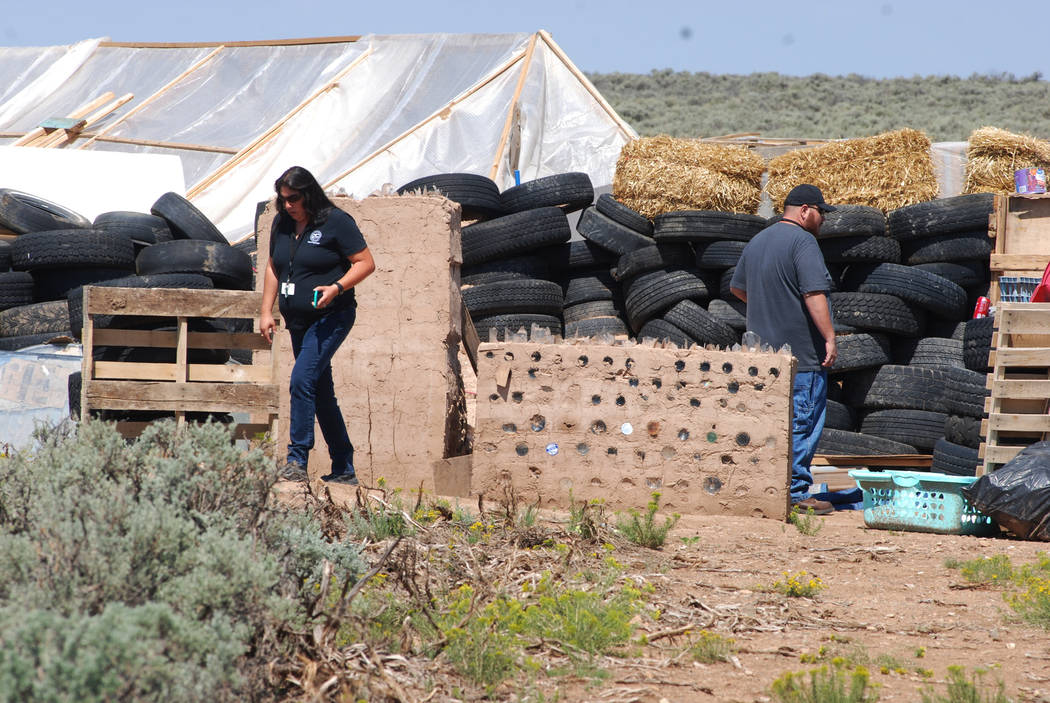 Taos County Planning Department officials Rachel Romero, left, and Eric Montoya survey property conditions at a disheveled living compound at Amalia, N.M., on Tuesday, Aug. 7, 2018. A New Mexico s ...