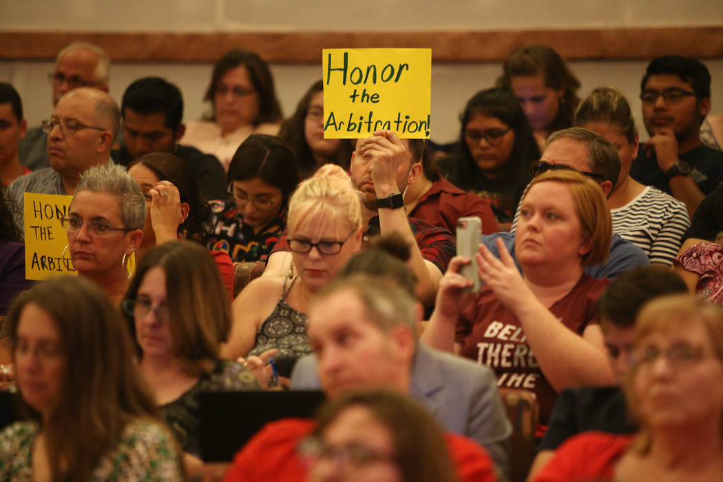 A person holds a sign saying "honor the arbitration" at a Clark County School District board meeting at the Clark County Government Center in Las Vegas, Thursday, Aug. 9, 2018. The distr ...