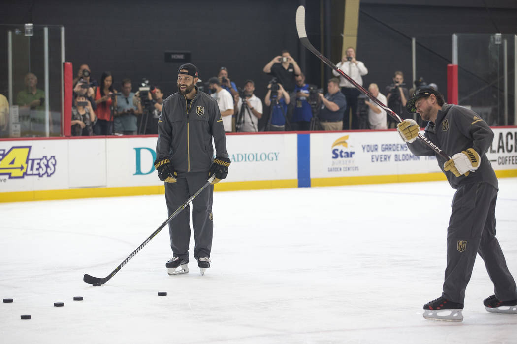 Vegas Golden Knights defenseman Deryk Engelland, left, looks on as NASCAR driver Kurt Busch takes a slap shot during a media event on Monday, Aug. 13, 2018, at City National Arena to promote the S ...
