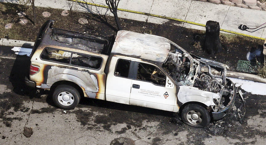 A burned West Valley City Community Preservation Code Enforcement vehicle is seen near the place where a structure fire and fatal shooting occurred in West Valley City, Utah, on Thursday, Aug. 9, ...