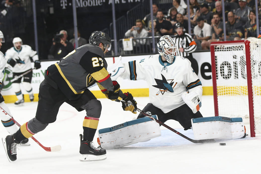 Golden Knights defenseman Shea Theodore (27) tries to get the puck in as San Jose Sharks goaltender Martin Jones (31) defends during the first period of Game 2 of an NHL hockey second-round playof ...