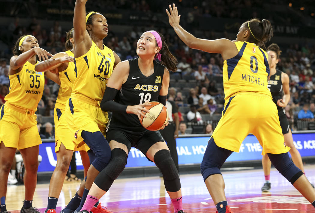 Las Vegas Aces center Ji-Su Park (19) looks for a shot through Indiana Fever defenders Kayla Alexander (40) and Kelsey Mitchell (0) during the second half of a WNBA basketball game at the Mandala ...