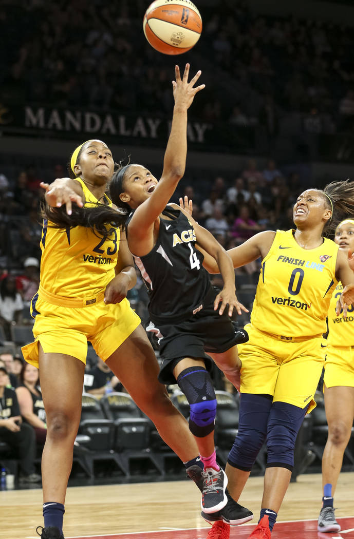 Las Vegas Aces guard Moriah Jefferson (4) takes a shot against Indiana Fever forward Stephanie Mavunga (23) and Fever guard Kelsey Mitchell (0) during the first half of a WNBA basketball game at t ...
