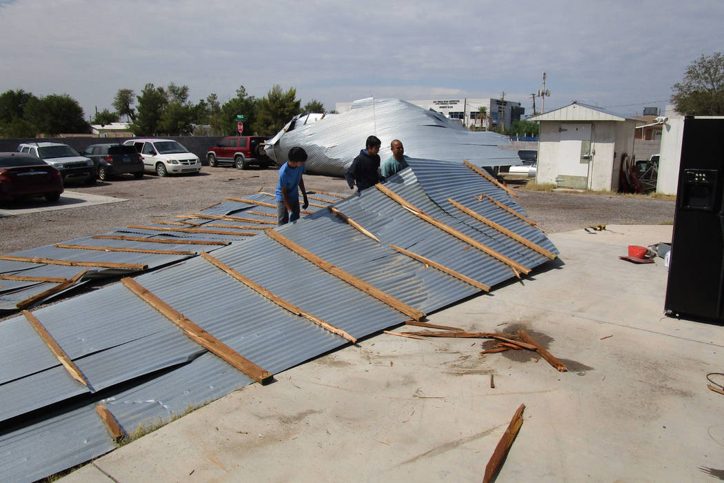 Workers try to dismantle a sheet metal awning that collapsed in Saturday night’s storm behind a business in east Las Vegas near Lake Mead Boulevard and Nellis Boulevard on Sunday, August 12, 201 ...
