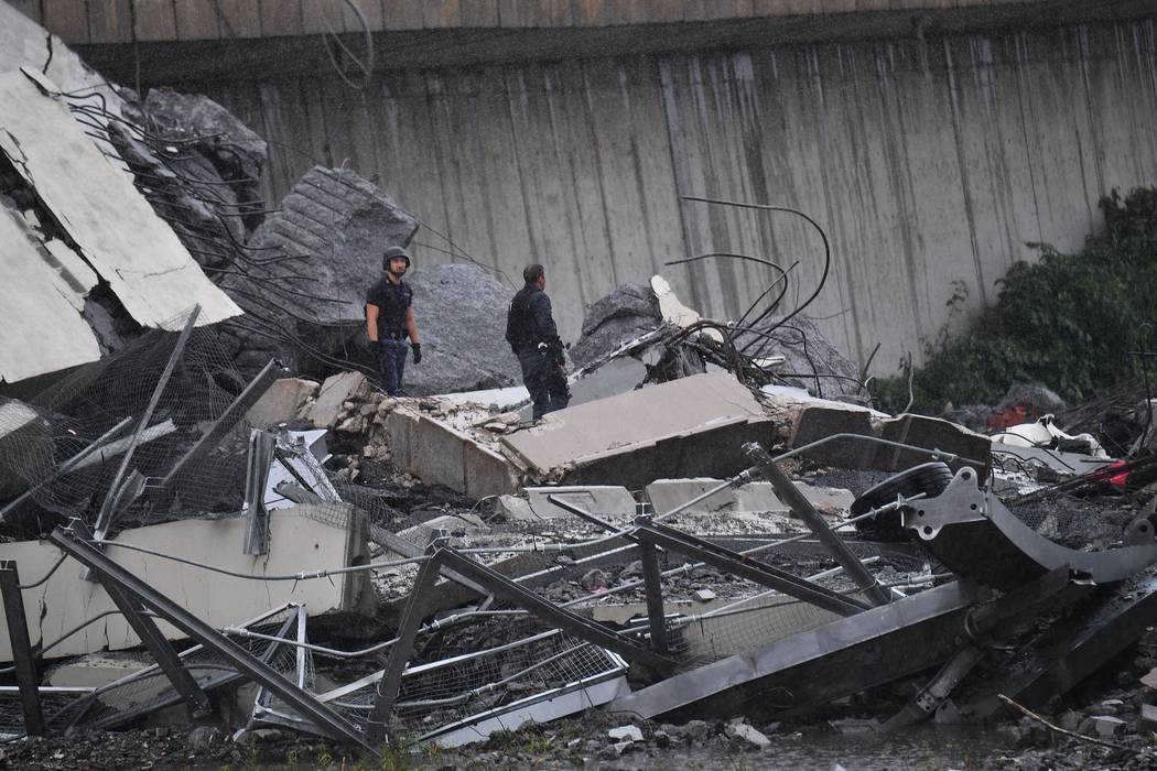 Rescuers work among the rubble of the Morandi highway bridge that collapsed in Genoa, northern Italy, Tuesday, Aug. 14, 2018. A large section of the bridge collapsed over an industrial area in the ...