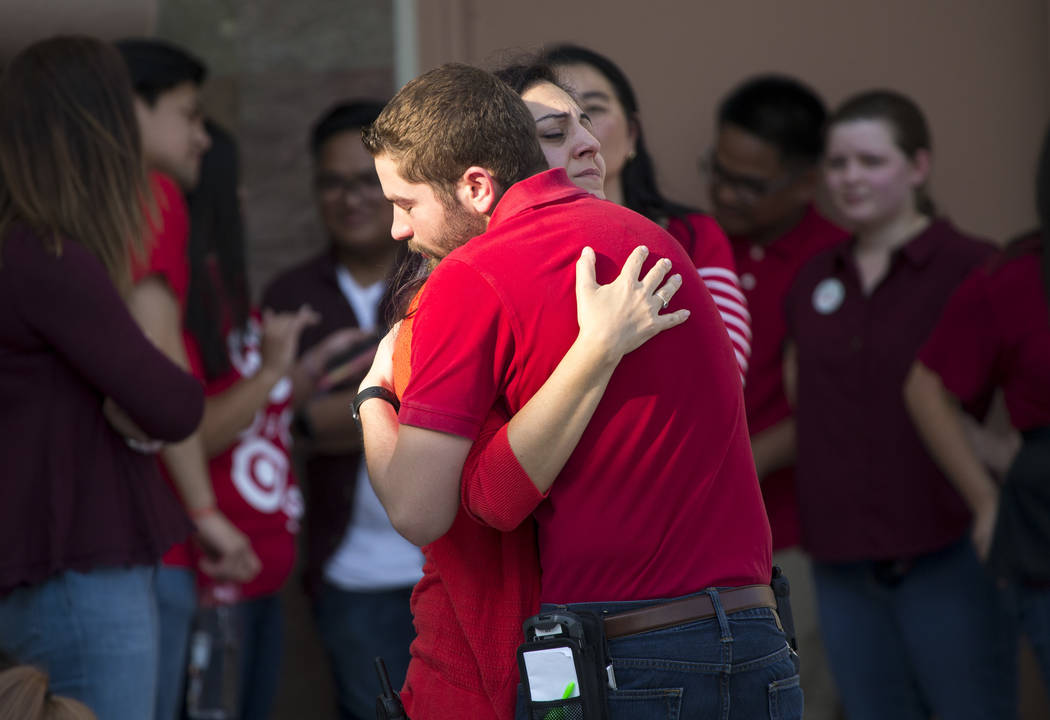 Unidentified Target department store employees comfort each other as Las Vegas police investigate an officer-involved shooting at a shopping complex near Blue Diamond Road and Arville Street in La ...