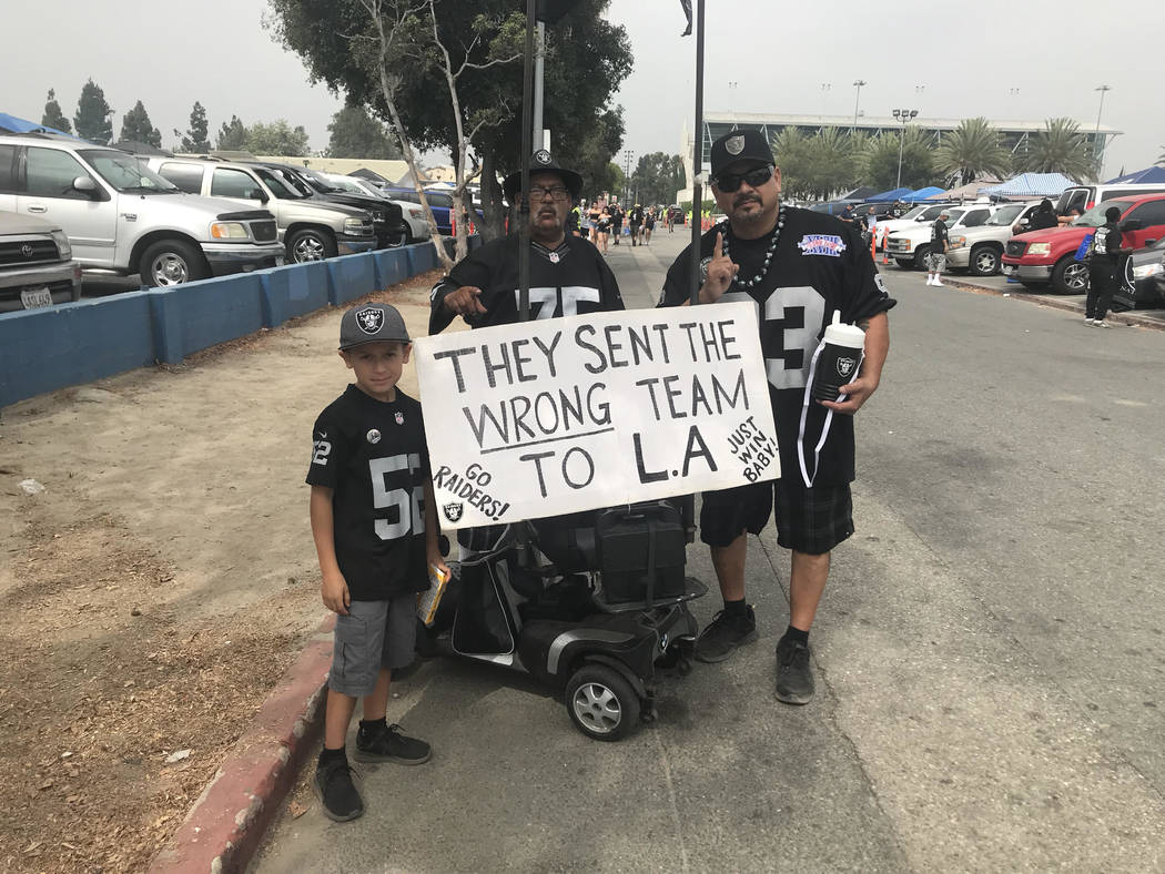 Javier Yi, right, a longtime Raiders fan, holds sign before Raiders played the Rams in Los Angeles on Saturday. (Gilbert Manzano)