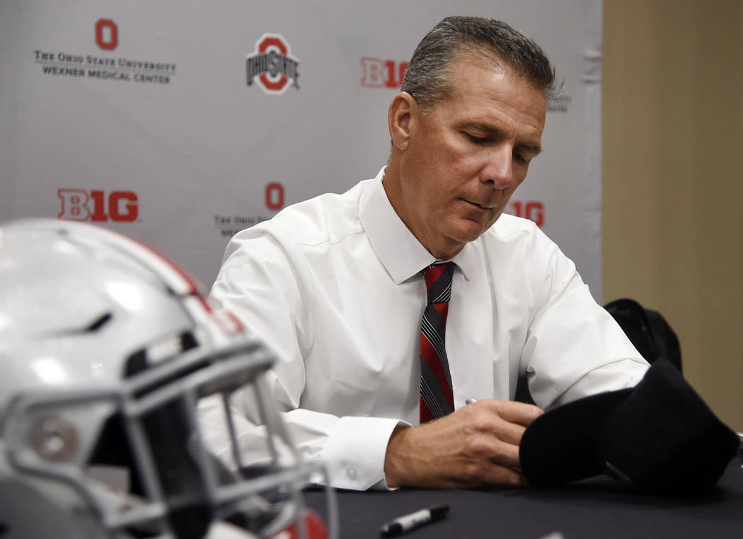 Ohio State head coach Urban Meyer autographs a hat at the Big Ten Conference NCAA college football media days in Chicago, Tuesday, July 24, 2018. (AP Photo/Annie Rice)