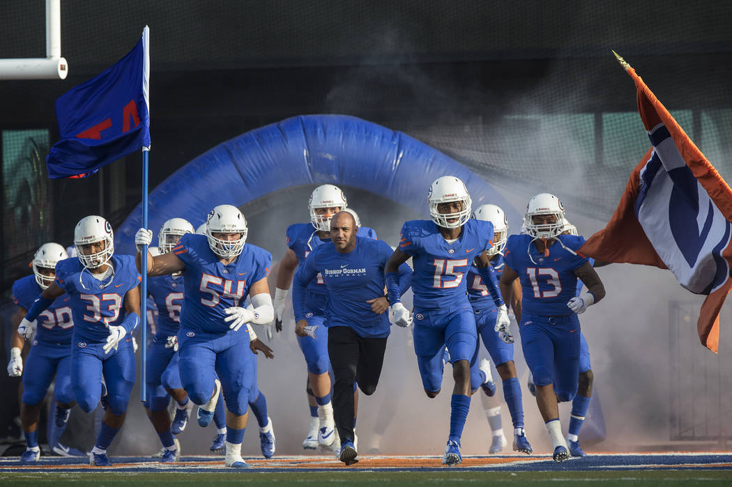 Bishop Gorman head coach Kenny Sanchez, middle, leads the Gaels onto the field before the start of their home matchup with Mater Dei on Friday, Aug. 24, 2018, at Bishop Gorman High School, in Las ...