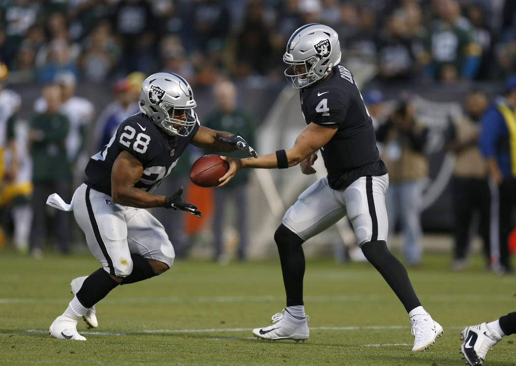Oakland Raiders quarterback Derek Carr (4) hands off to running back Doug Martin (28) during the first half of an NFL preseason football game in Oakland, Calif., Friday, Aug. 24, 2018. (AP Photo/D ...