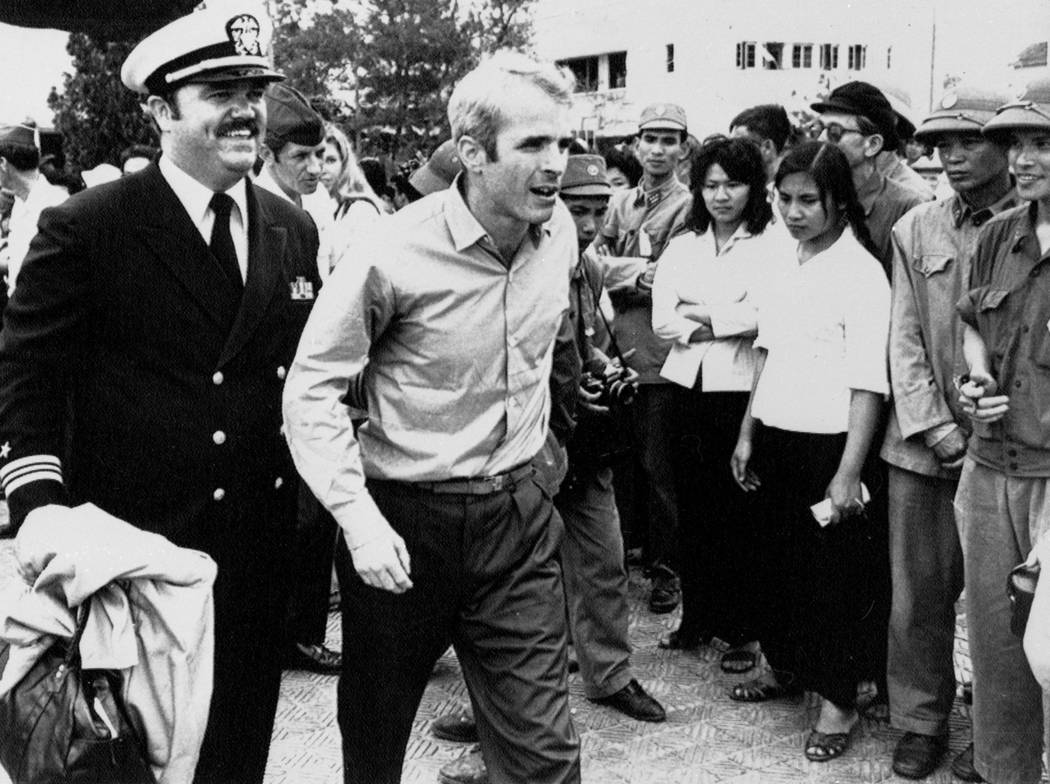 John S. McCain III is escorted by Lt. Cmdr. Jay Coupe Jr., public relations officer, March 14, 1973, to Hanoi's Gia Lam Airport after the POW was released. (AP Photo/Horst Faas)