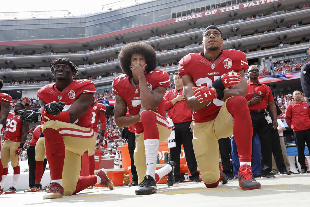 In this Oct. 2, 2016 file photo, from left, San Francisco 49ers outside linebacker Eli Harold, quarterback Colin Kaepernick and safety Eric Reid kneel during the national anthem before an NFL foot ...