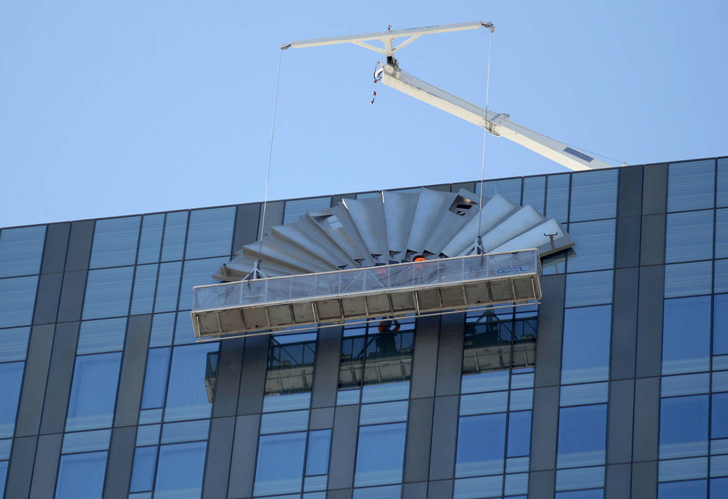 A work crew removes the Mandarin Oriental fan on the top of the Waldorf Astoria on the first day for the new Las Vegas hotel on the Strip Friday, Aug. 31, 2018. Hilton Hotels started to rebrand th ...