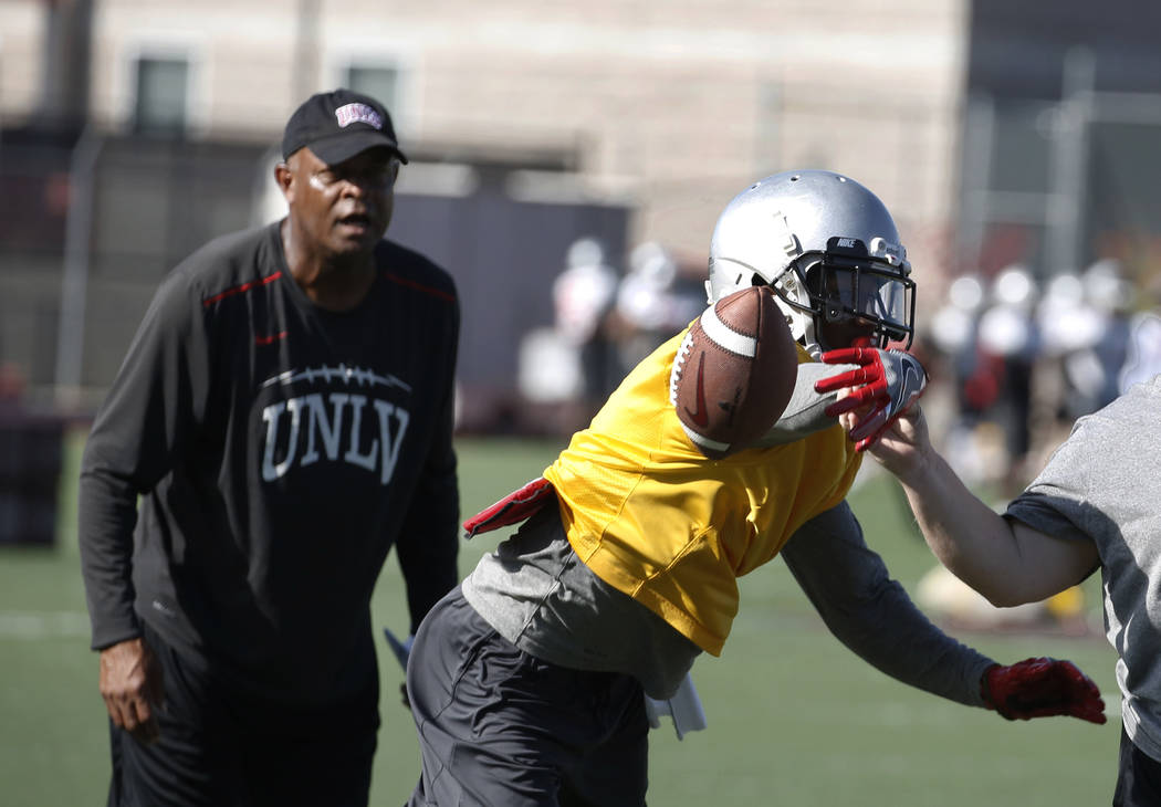 UNLV cornerback Alex Perry, right, deflects a pass as defensive line coach Tony Samuel, left, looks on during team practice on Wednesday, Sept. 5, 2018, in Las Vegas. (Bizuayehu Tesfaye/Las Vegas ...