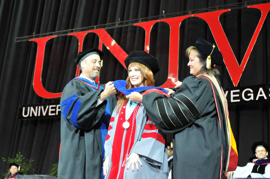 UNLV Janet King, center, takes part in a hooding ceremony for doctoral graduates during UNLV's spring commencement ceremony May 13, 2017. Putting on King's hood is Dr. Kendall Hartley, left, and D ...