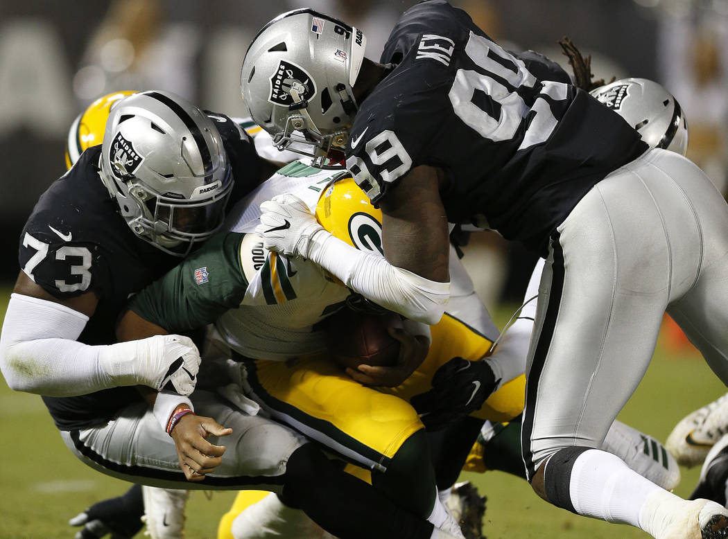 Green Bay Packers quarterback Brett Hundley, center, is sacked by Oakland Raiders defensive tackle Maurice Hurst (73) and defensive end Fadol Brown, hidden, during the first half of an NFL preseas ...