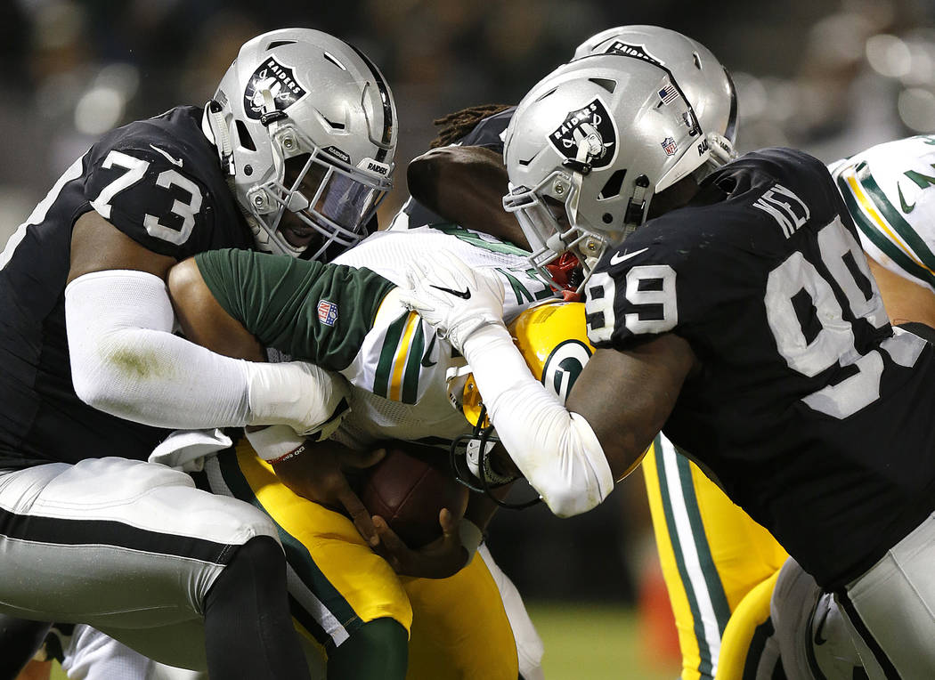 Green Bay Packers quarterback Brett Hundley, center, is sacked by Oakland Raiders defensive tackle Maurice Hurst (73) and defensive end Fadol Brown, obscured, during the first half of an NFL prese ...