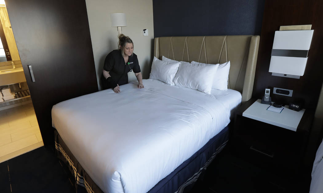 Rani Accettola, a housekeeper at the Embassy Suites by Hilton hotel in Seattle's Pioneer Square neighborhood, demonstrates how she smoothes the sheets on a bed at the hotel in Seattle on Wednesday ...