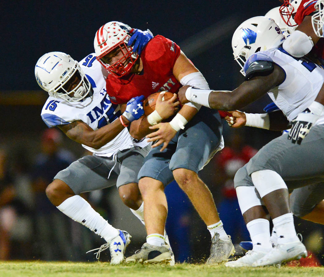 Liberty's Kyle Beaudry (4) is tackled by IMG Academy defenseman Jayden Curry (15) during a game at Liberty High School in Henderson on Friday, Sept. 7, 2018. IMG Academy won 35-0. Brett Le Blanc L ...