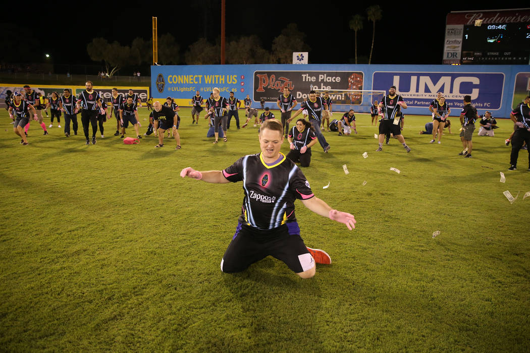 Fans rush to collect a piece of the $5,000 dropped from a helicopter at half time during an USL soccer game between the Las Vegas Lights and LA galaxy II at Cashman Field in Las Vegas, Saturday, S ...