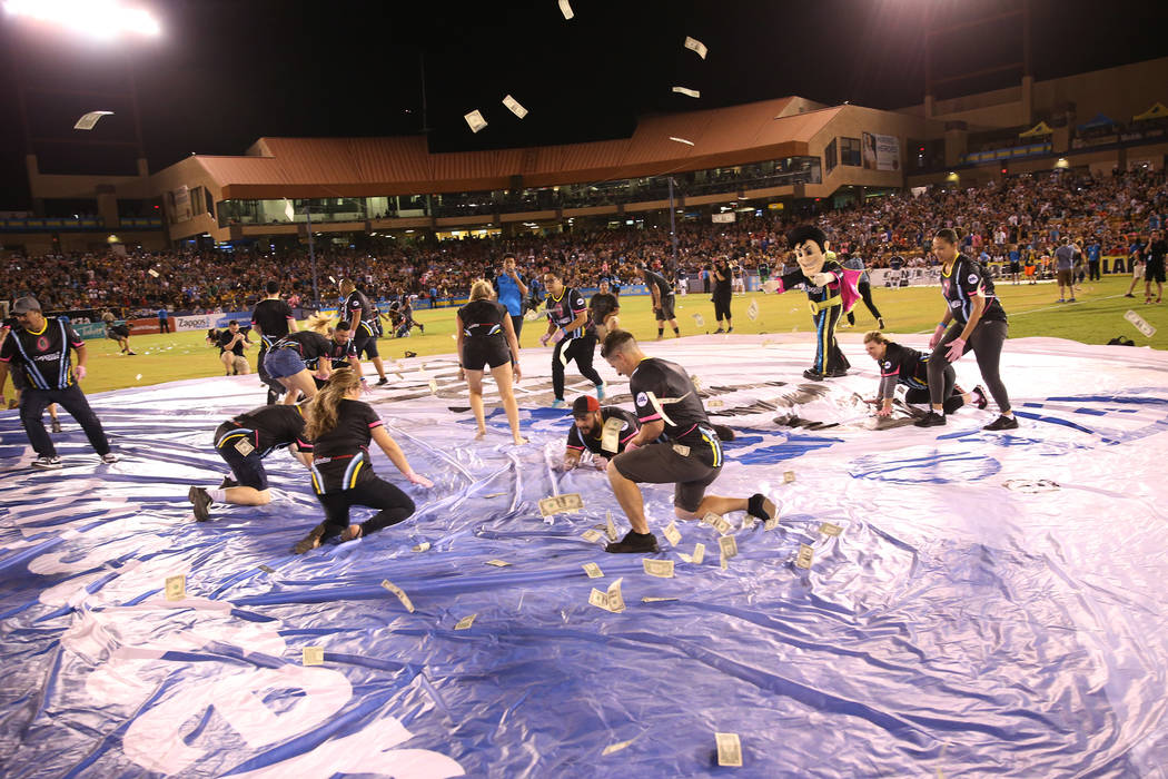 Fans rush to collect a piece of the $5,000 dropped from a helicopter at half time during an USL soccer game between the Las Vegas Lights and LA galaxy II at Cashman Field in Las Vegas, Saturday, S ...