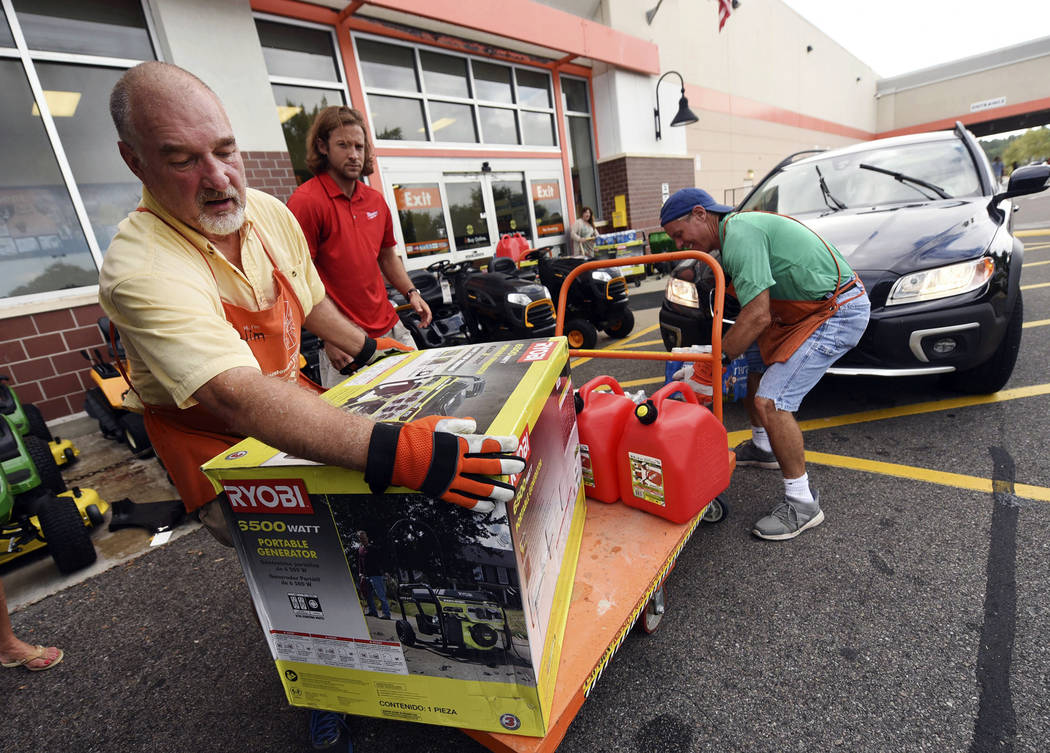 Jim Craig, David Burke and Chris Rayner load generators as people buy supplies at The Home Depot on Monday, Sept. 10, 2018, in Wilmington, N.C. Hurricane Florence rapidly strengthened into a poten ...