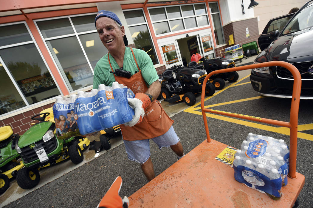 Chris Rayner helps customers load their cars as they buy supplies at The Home Depot on Monday, Sept. 10, 2018, in Wilmington, N.C. Hurricane Florence rapidly strengthened into a potentially catast ...