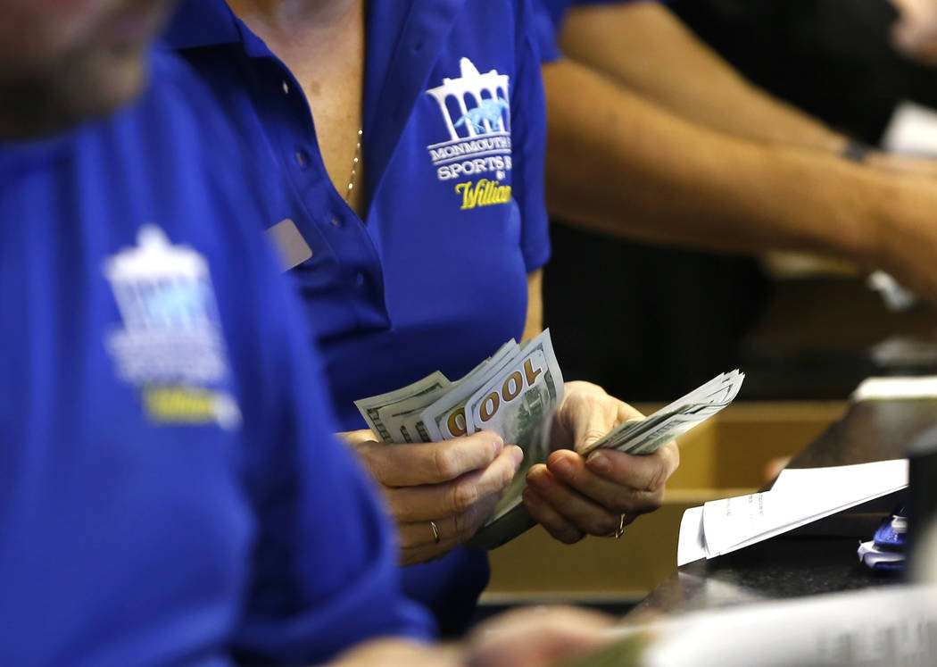 Ticket writers count cash before the opening of Monmouth Park Sports Book at Monmouth Park Racetrack, in Oceanport, N.J. on Thursday, June 14, 2018. (AP Photo/Noah K. Murray, File)