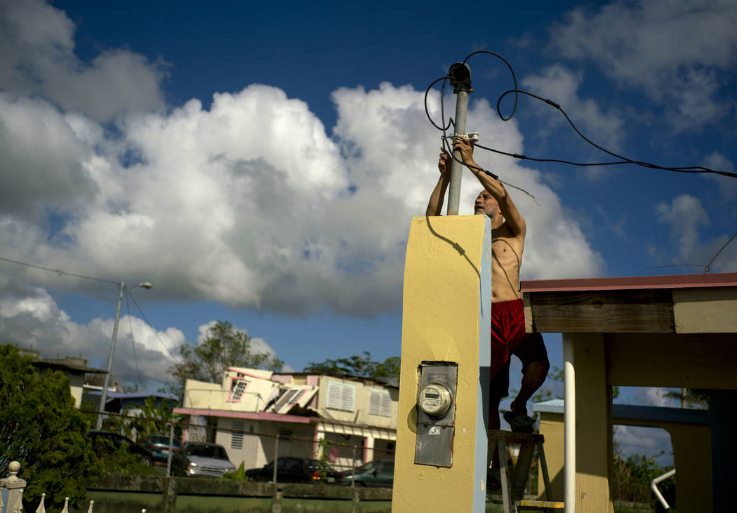 A resident tries to connect electrical lines downed by Hurricane Maria in preparation for when electricity is restored in Toa Baja, Puerto Rico, about three weeks after the storm, Oct. 13, 2017. L ...