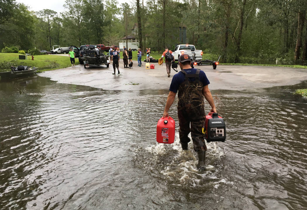 Kevin Knox carries gas and a generator after being rescued from his flooded neighborhood from the effects of Florence, now a tropical storm, in New Bern, N.C., on Saturday, Sept. 15, 2018. (AP Pho ...