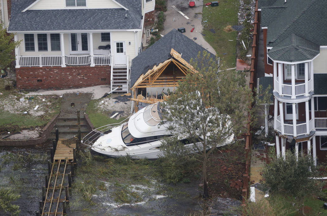 A yacht sits on the Neuse river bank in between buildings after hurricane Florence passed through the area in New Bern, NC., Saturday, Sept. 15, 2018. (AP Photo/Steve Helber)