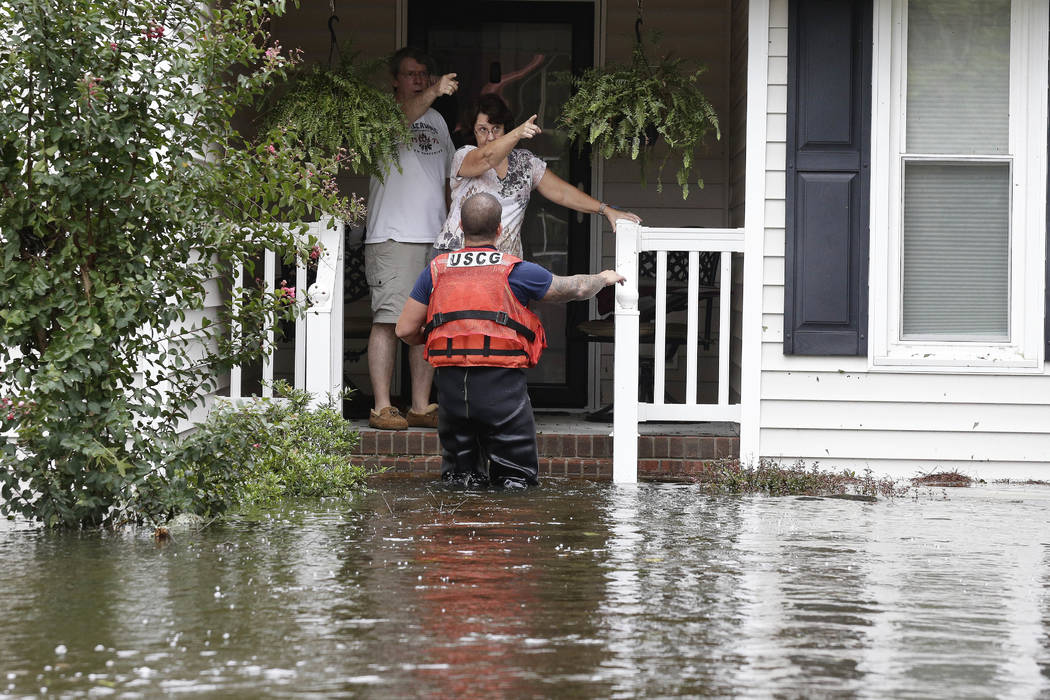 A member of the U.S. Coast Guard assists Roger and Susan Hedgepeth in Lumberton, N.C., Sunday, Sept. 16, 2018, following flooding from Hurricane Florence. (AP Photo/Gerry Broome)