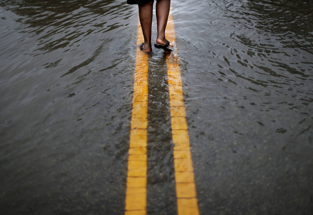 Helen McKoy walks down a flooded street in her neighborhood as Florence continues to dump heavy rain in Fayetteville, N.C., Sunday, Sept. 16, 2018. (AP Photo/David Goldman)